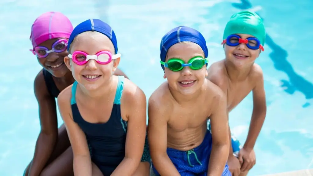 Enfants en cours de natation portant des bonnets de bain personnalisés enfant aux couleurs du club